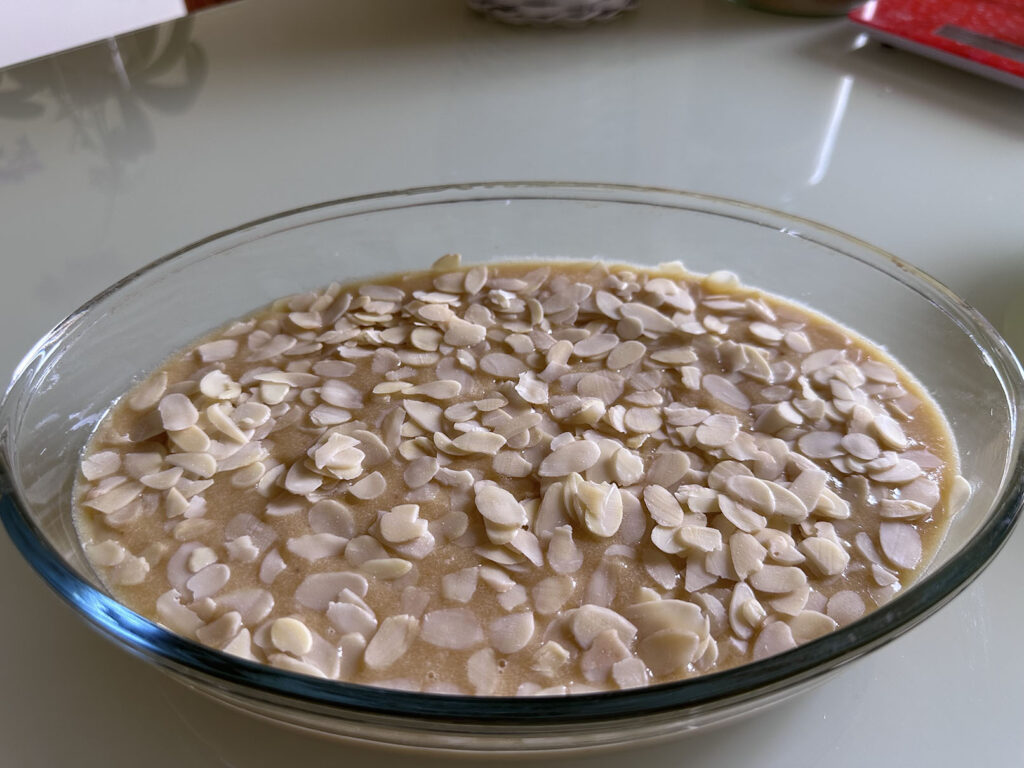 Pâte crue dans un moule en verre recouverte d'amandes effilées avant cuisson